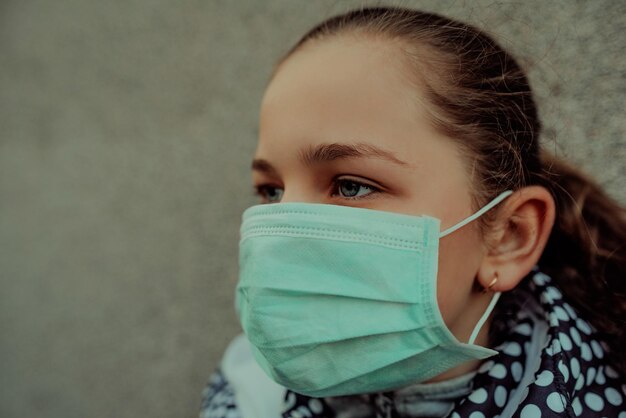 Concepto de coronavirus y contaminación del aire pm2.5. Niña pequeña con máscara para proteger pm2.5. Niño niña encarcelada en casa para proteger el virus de la corona. Coronavirus de Wuhan y síntomas del virus epidémico.