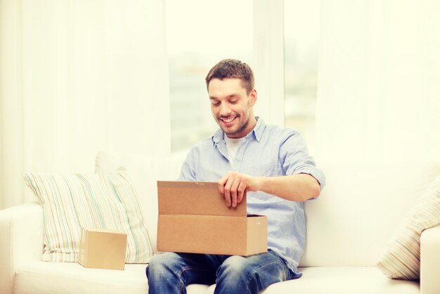 Concepto de correo, hogar y estilo de vida - hombre sonriente con cajas de cartón en casa