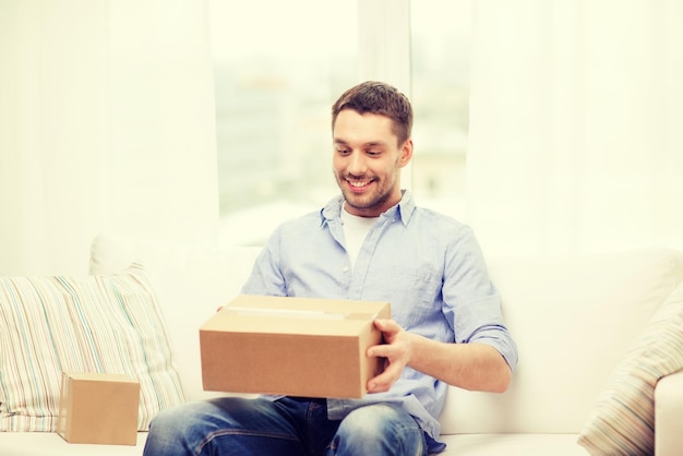 Concepto de correo, hogar y estilo de vida - hombre sonriente con cajas de cartón en casa