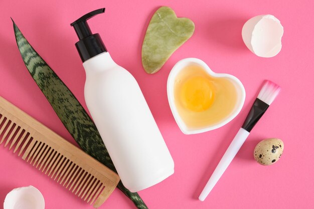 Foto concepto de cosmética natural a base de huevo maqueta botella peine gua sha raspadores y huevo crudo