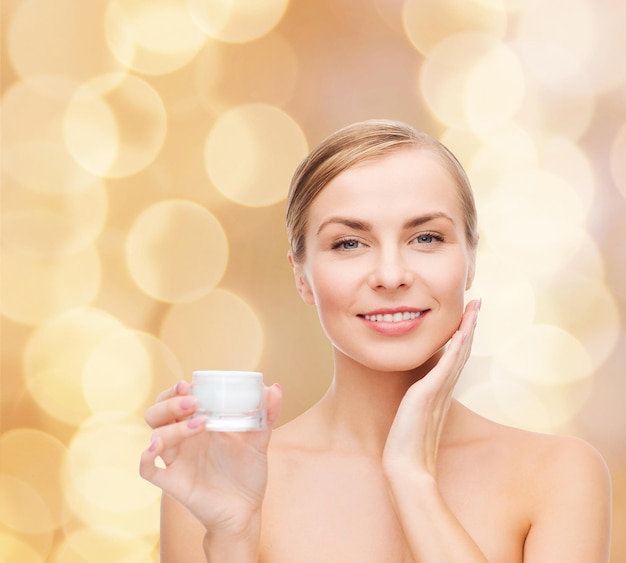 concepto de cosmética, salud y belleza - hermosa mujer aplicando crema en su piel