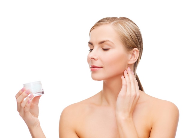 concepto de cosmética, salud y belleza - hermosa mujer aplicando crema en su piel