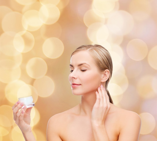 concepto de cosmética, salud y belleza - hermosa mujer aplicando crema en su piel