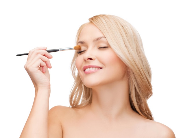 concepto de cosmética, salud y belleza - mujer hermosa con los ojos cerrados y pincel de maquillaje