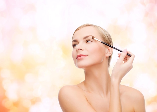 concepto de cosmética, salud y belleza - mujer hermosa con pincel de maquillaje