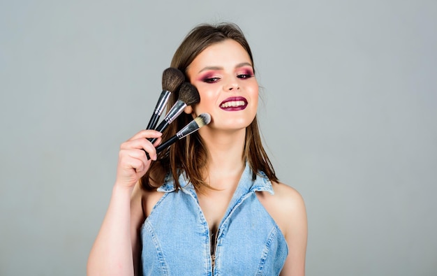 Concepto de cosméticos de maquillaje Enfatiza la feminidad Chica aplica sombras de ojos Cuidado de la piel Verse bien y sentirse seguro Mujer aplicando pincel de maquillaje Suministros de maquillaje profesional Diferentes pinceles