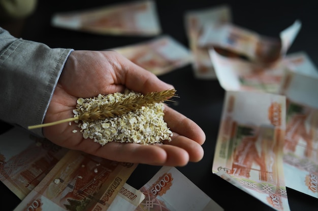 El concepto del costo del grano Billetes de 5000 rublos alrededor de un puñado de grano molido Hambre mundial