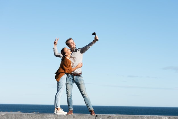 Concepto de creación de contenido de medios sociales Una pareja feliz grabándose y vlogueando en un día soleado en la playa