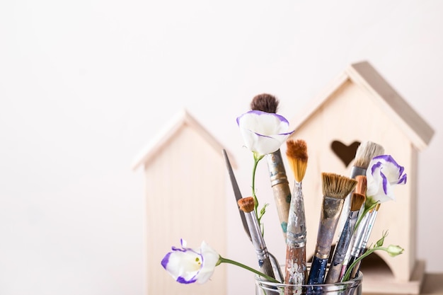 Concepto de creatividad artística. Juego de pinceles y casa de madera para decoración sobre fondo blanco.