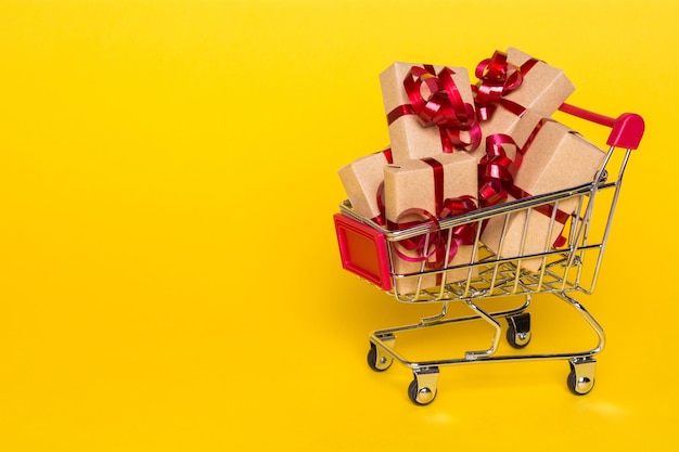 Concepto creativo con carrito de compras con regalos sobre un fondo amarillo