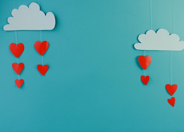 Concepto creativo día de San Valentín vacaciones amor foto de nube de papel hecho a mano lloviendo con corazones sobre fondo azul.