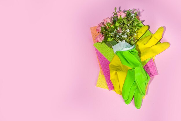 Concepto creativo de limpieza de primavera brillante. Herramientas, botellas, accesorios para la limpieza de la casa con flores y hojas de primavera cuelgan en el tendedero, caja, espacio de copia de luz soleada brillante