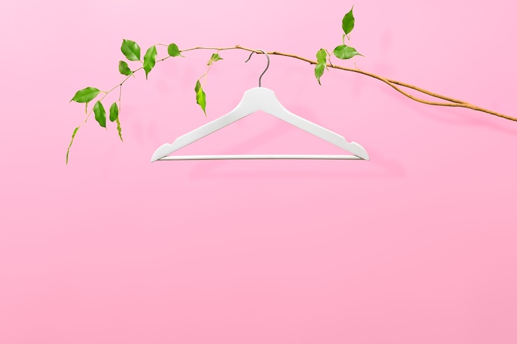 Foto concepto creativo de venta de verano o primavera sobre un fondo rosa con espacio de copia percha blanca en una rama delgada con hojas