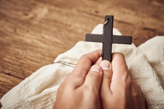 Concepto de cristiano. primer plano de la mano rezando sosteniendo un fondo de cruz negra de Jesucristo