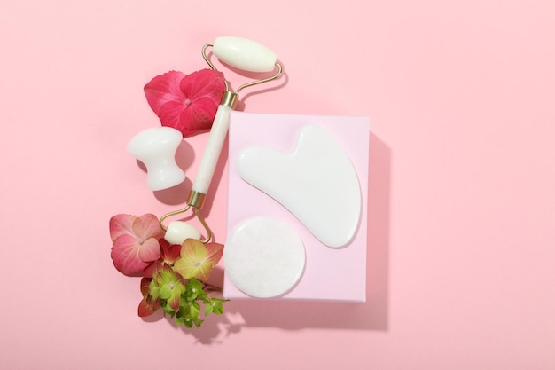 Concepto de cuidado facial con kit gua sha sobre fondo rosa