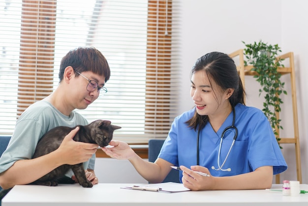 Concepto de cuidado de mascotas Veterinaria femenina examinando al gato y escribiendo la receta en el portapapeles