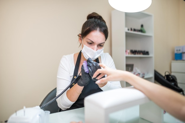 Concepto de cuidado de uñas Manicurist hace una manicura a una chica cliente en un salón de belleza