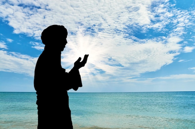 Concepto de cultura islámica. Silueta de hombre rezando en el fondo del mar y el hermoso cielo