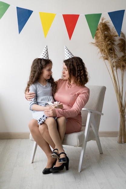 Concepto de cumpleaños. La niña se sienta en los brazos de su madre.