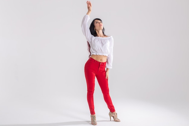 Concepto de danza latina, improvisación, danza contemporánea y de moda - joven y bella mujer bailando sobre fondo blanco de estudio