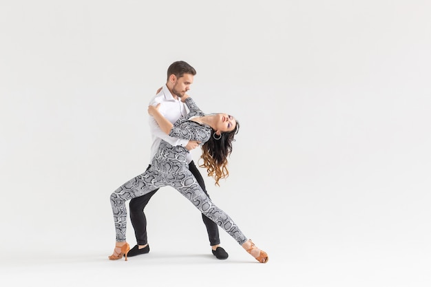 Concepto de danza social: adultos felices activos bailando bachata juntos sobre fondo blanco con espacio de copia