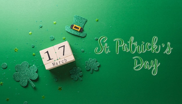 Concepto de decoración del Día de San Patricio feliz hecho de calendario de madera de hoja de trébol de tréboles y sombrero de duende sobre fondo verde