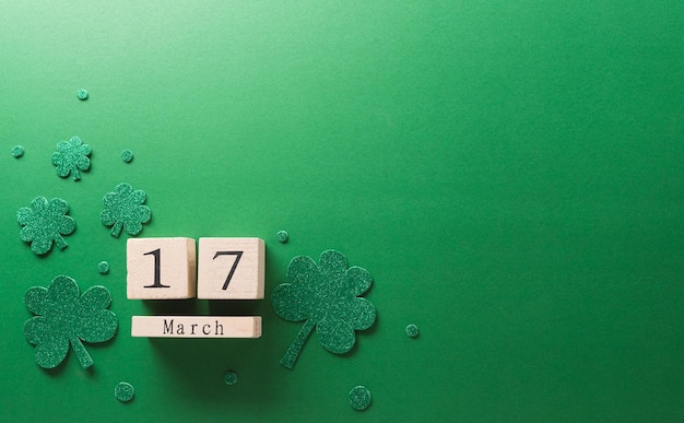 Concepto de decoración del Día de San Patricio feliz hecho de calendario de madera de hoja de trébol de tréboles y sombrero de duende sobre fondo verde