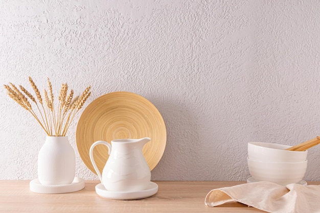 El concepto de la decoración de una encimera de madera de cocina moderna con platos blancos de cerámica y un jarrón con mazorcas de maíz un espacio para copiar