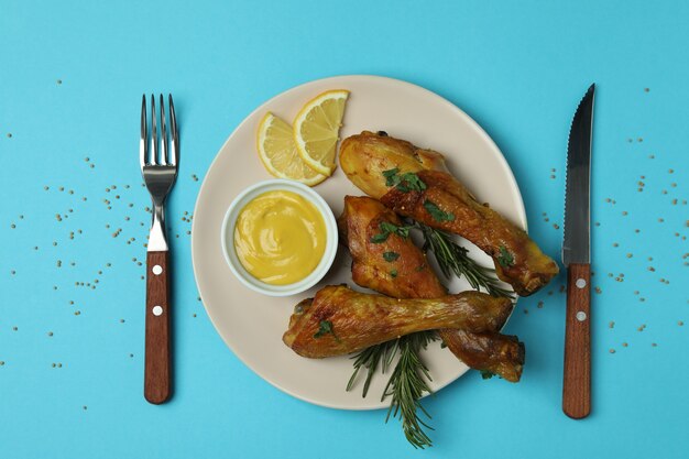 Concepto de deliciosa comida con plato de muslos de pollo asado sobre fondo azul.