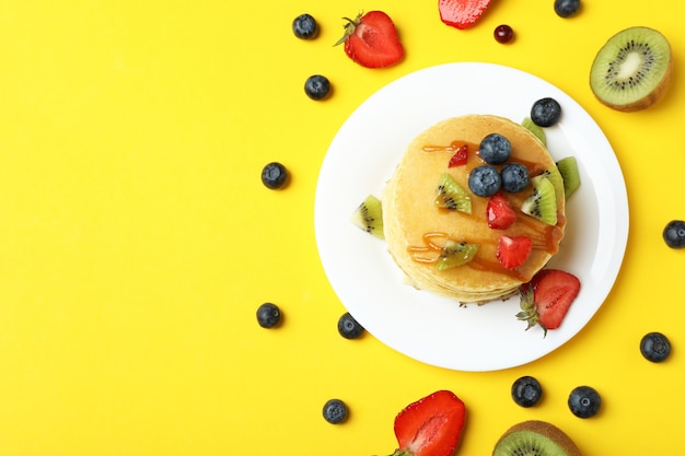 Concepto de delicioso postre con panqueques sobre fondo amarillo