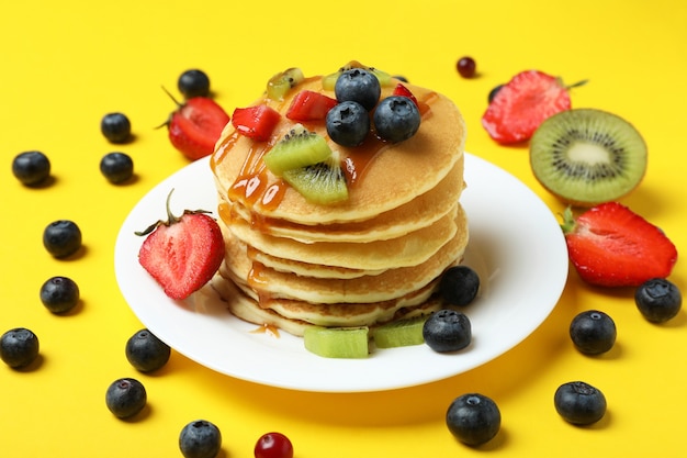 Concepto de delicioso postre con panqueques sobre fondo amarillo