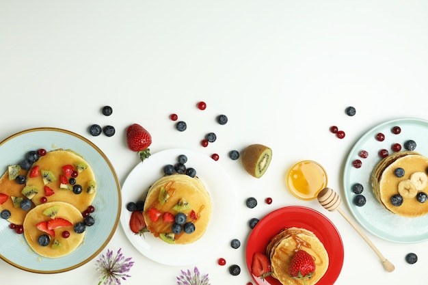 Concepto de delicioso postre con panqueques sobre fondo blanco.