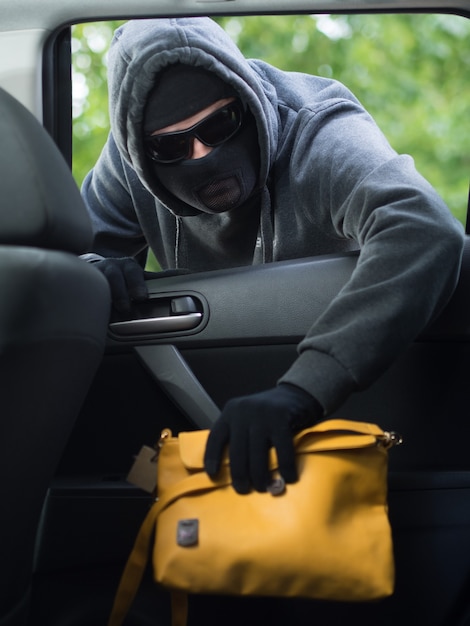 Concepto de delito de transporte ladrón robando la bolsa del coche