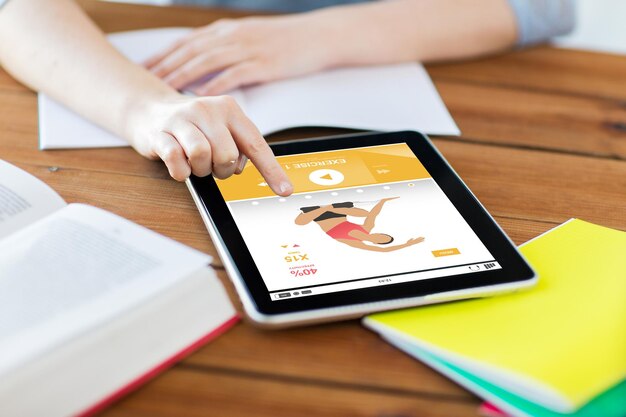 concepto de deporte, educación, tecnología e Internet: cierre de una estudiante con una aplicación de fitness en una tableta y un portátil en casa