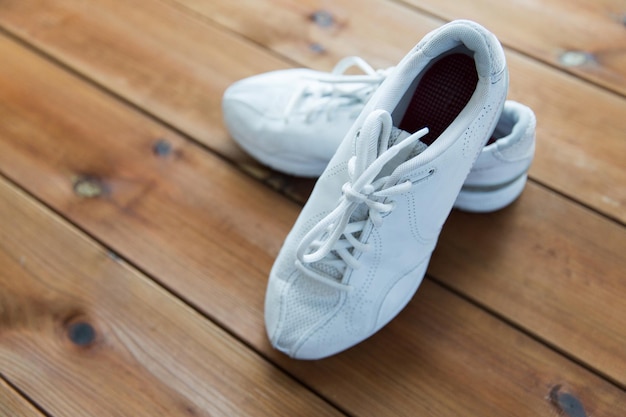 Concepto de deporte, fitness, calzado, calzado y objetos - cerca de zapatillas de deporte en el piso de madera