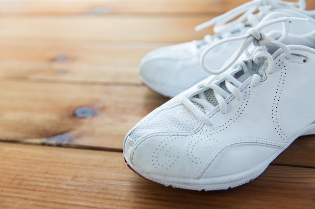 Concepto de deporte, fitness, calzado, calzado y objetos - cerca de zapatillas de deporte en el piso de madera