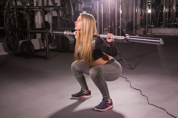 Concepto de deporte, fitness, entrenamiento y felicidad - mujer deportiva con barra en el gimnasio