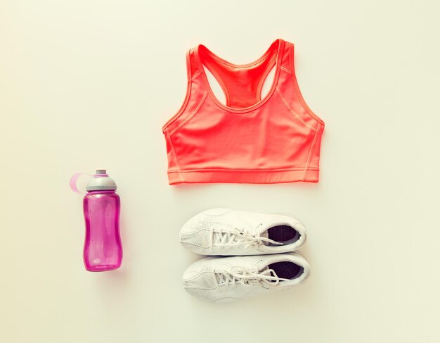 concepto de deporte, fitness, estilo de vida saludable y objetos - primer plano de ropa deportiva femenina y conjunto de botellas