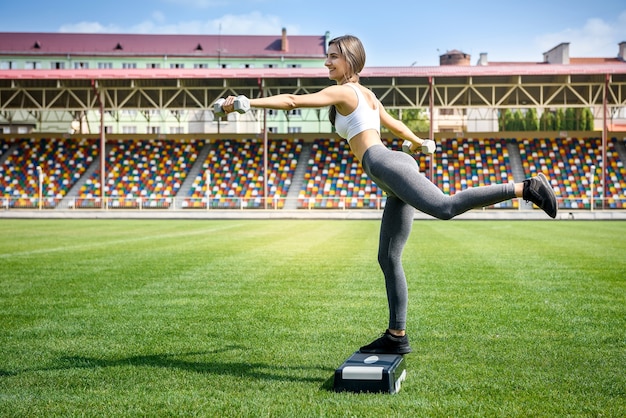 Concepto de deporte y fitness. Mujer haciendo ejercicios al aire libre sobre la hierba verde