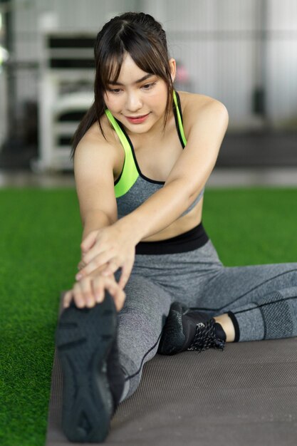 Concepto de deporte y recreación. Mujer en ropa deportiva haciendo estiramientos de piernas listos para el ejercicio de entrenamiento con peso corporal.