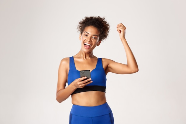 Foto concepto de deporte y tecnología. atractiva mujer afroamericana athelte logra su objetivo en la aplicación worout