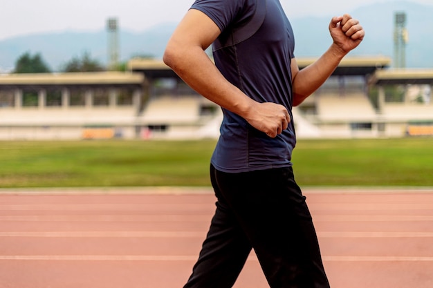 Concepto de deportes y recreación un joven adulto masculino corriendo a baja velocidad en el estadio deportivo como su rutina saludable en la noche.