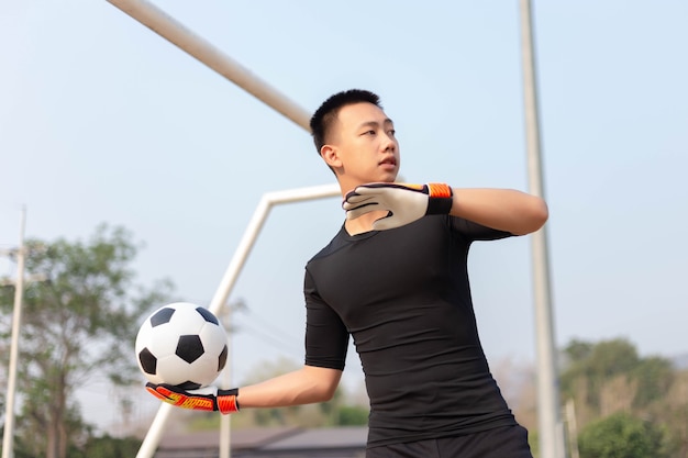 Concepto de deportes y recreación un portero masculino parado frente a la portería lanzando una pelota como distribuida a un jugador después de proteger la portería.