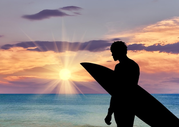 Concepto deportivo. Silueta de un surfista en la playa en el fondo del mar al atardecer