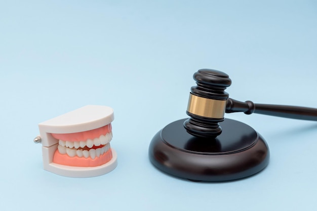 Concepto de derecho dental y justicia médica con martillo y modelo dental en fondo azul