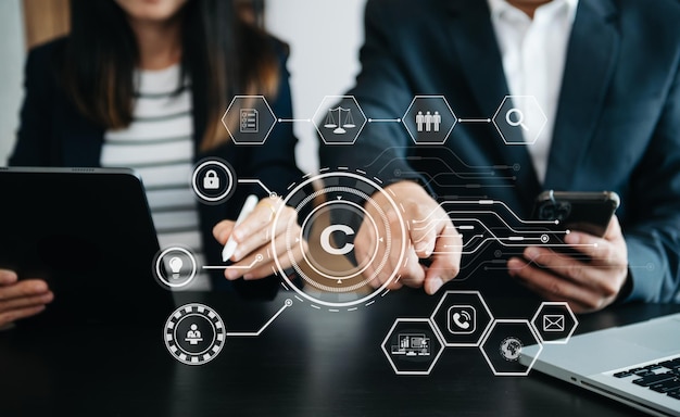 Concepto de derechos de autor o patentes Equipo empresarial analizando datos y usando teléfonos inteligentes y tabletas con pantalla virtual icono de derechos de autor licencia de marca Propiedad de creación contra la piratería en officexA