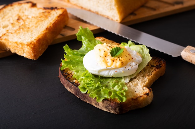 Concepto de desayuno de alimentos orgánicos Huevo escalfado casero o huevos Benedict en pan de masa fermentada tostado en pizarra negra