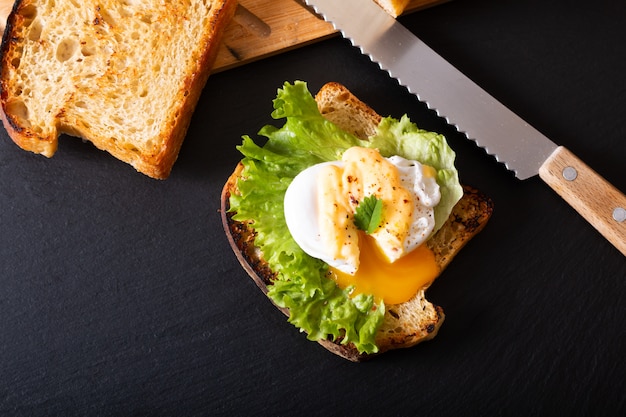 Concepto de desayuno de alimentos orgánicos Huevo escalfado casero o huevos Benedict en pan de masa fermentada tostado en pizarra negra