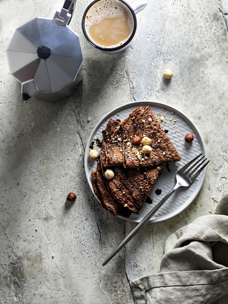 Concepto de desayuno Crepes de chocolate con nueces y salsa de chocolate en una vista superior de fondo texturizado