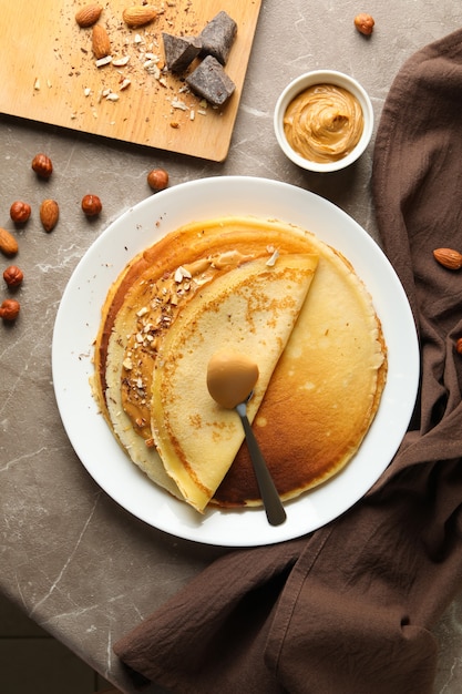 Concepto de desayuno con crepes con mantequilla de maní y nueces en mesa gris